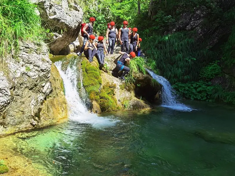 Grupa u opremi za kanjoning kraj slapova i zelenog bazena u kanjonu Bijele