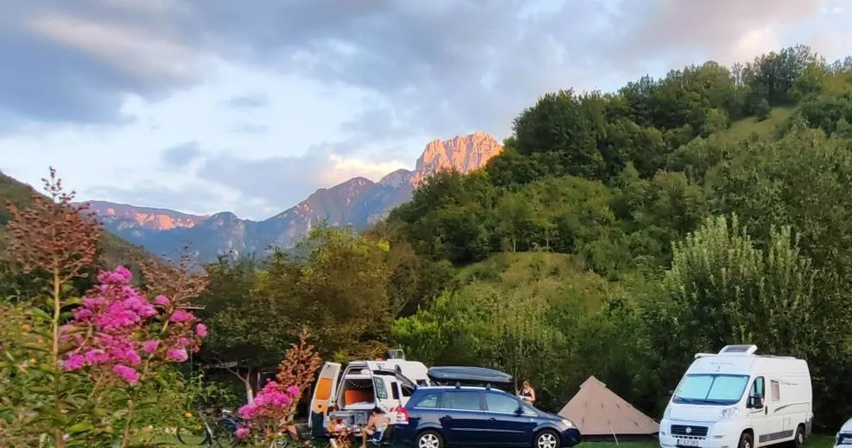 Vrhovi Prenja iznad šume i livade Ravna Campinga u zlatnom svjetlu